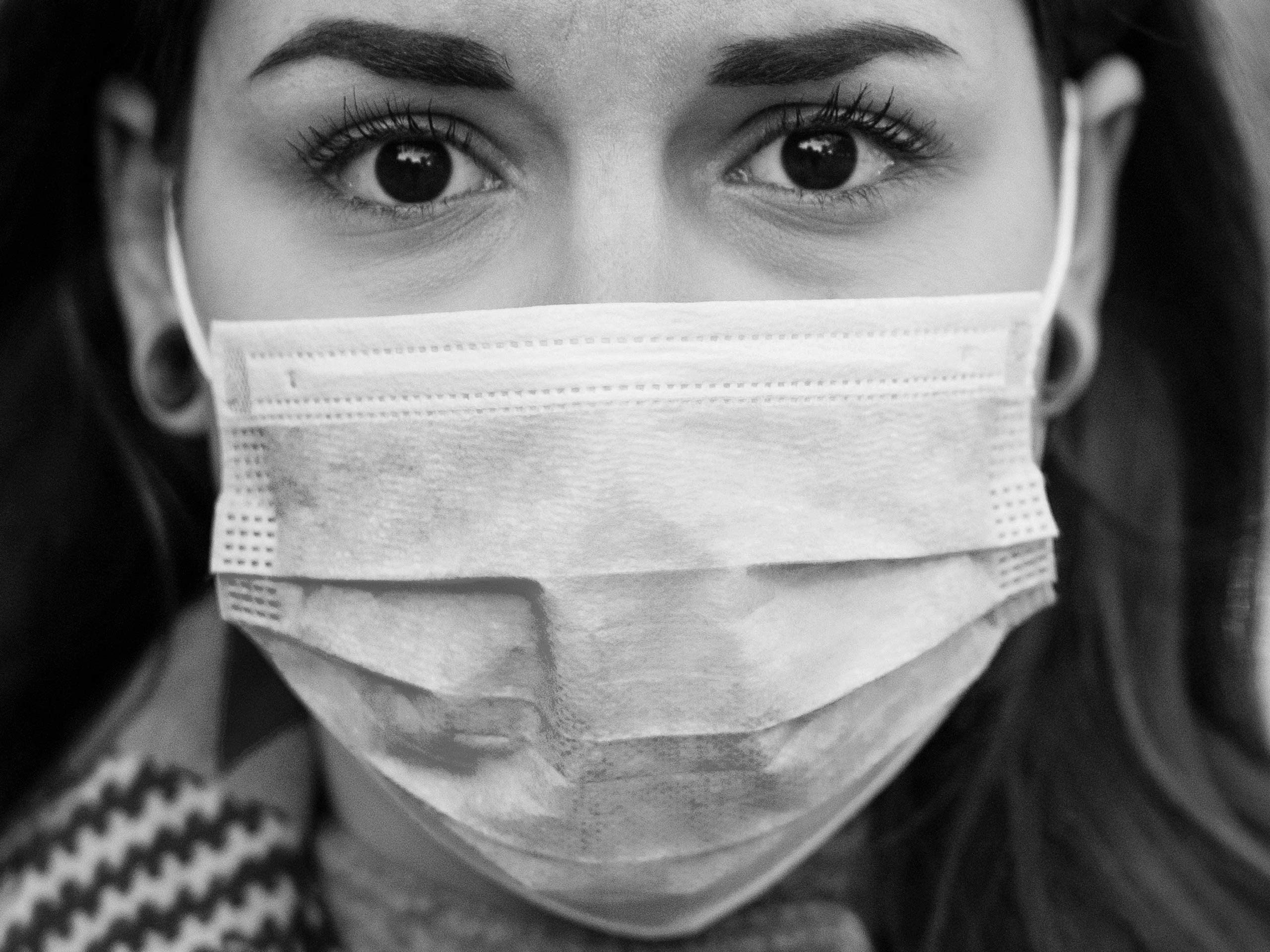 A black and white picture of a woman wearing an anti covid-19 mask