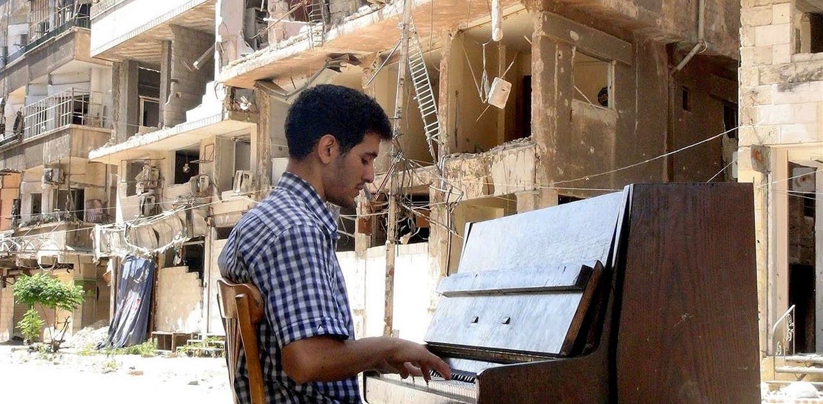 A man wearing a flannel shirt while playing piano