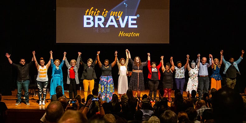 A large group of people holding hands while victoriously pointing them up