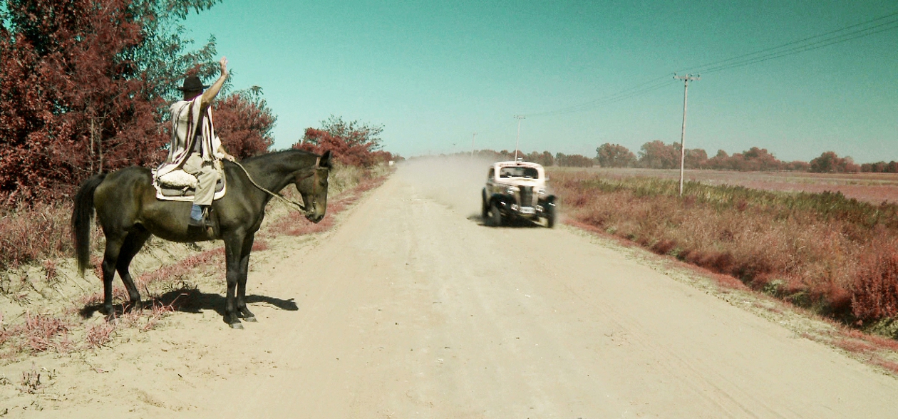 A man in a horse greeting a vintage race car