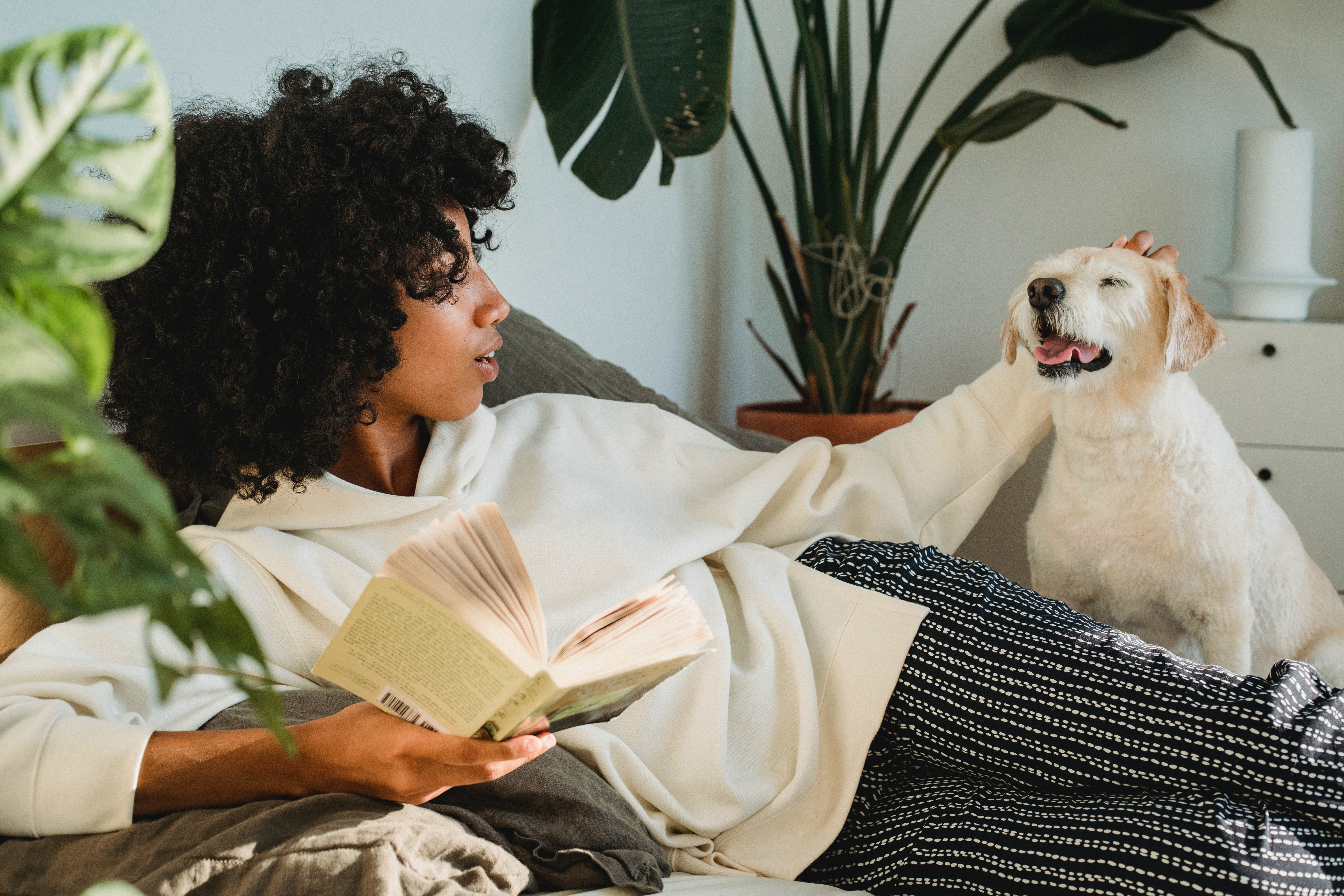 A black woman holding a book while petting a dog