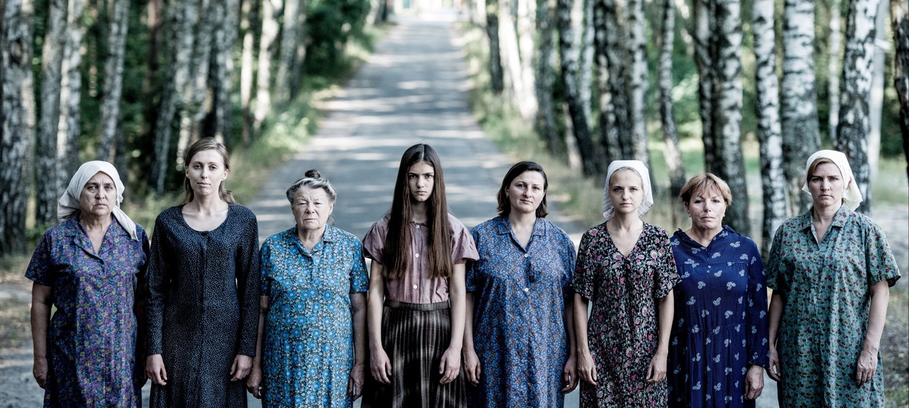 A group of women of different ages standing next to each other in a forest