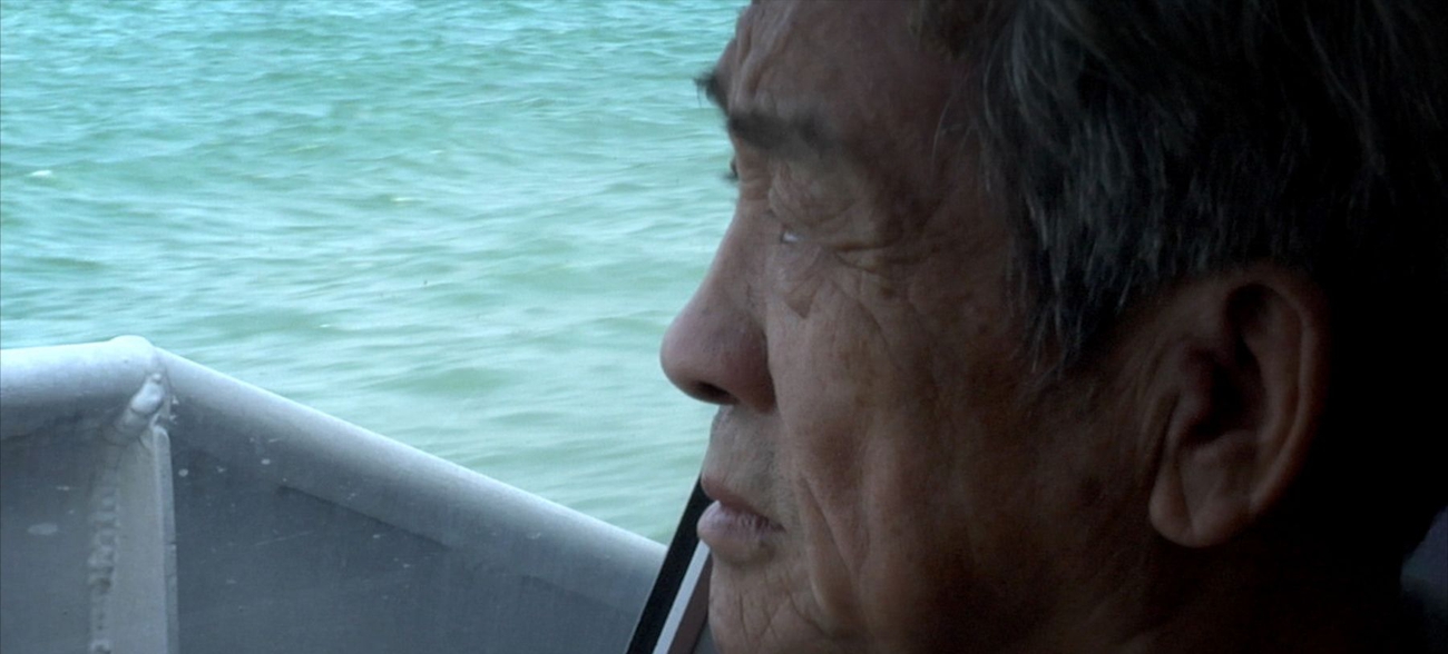 A Chinese man in a boat looking to the horizon