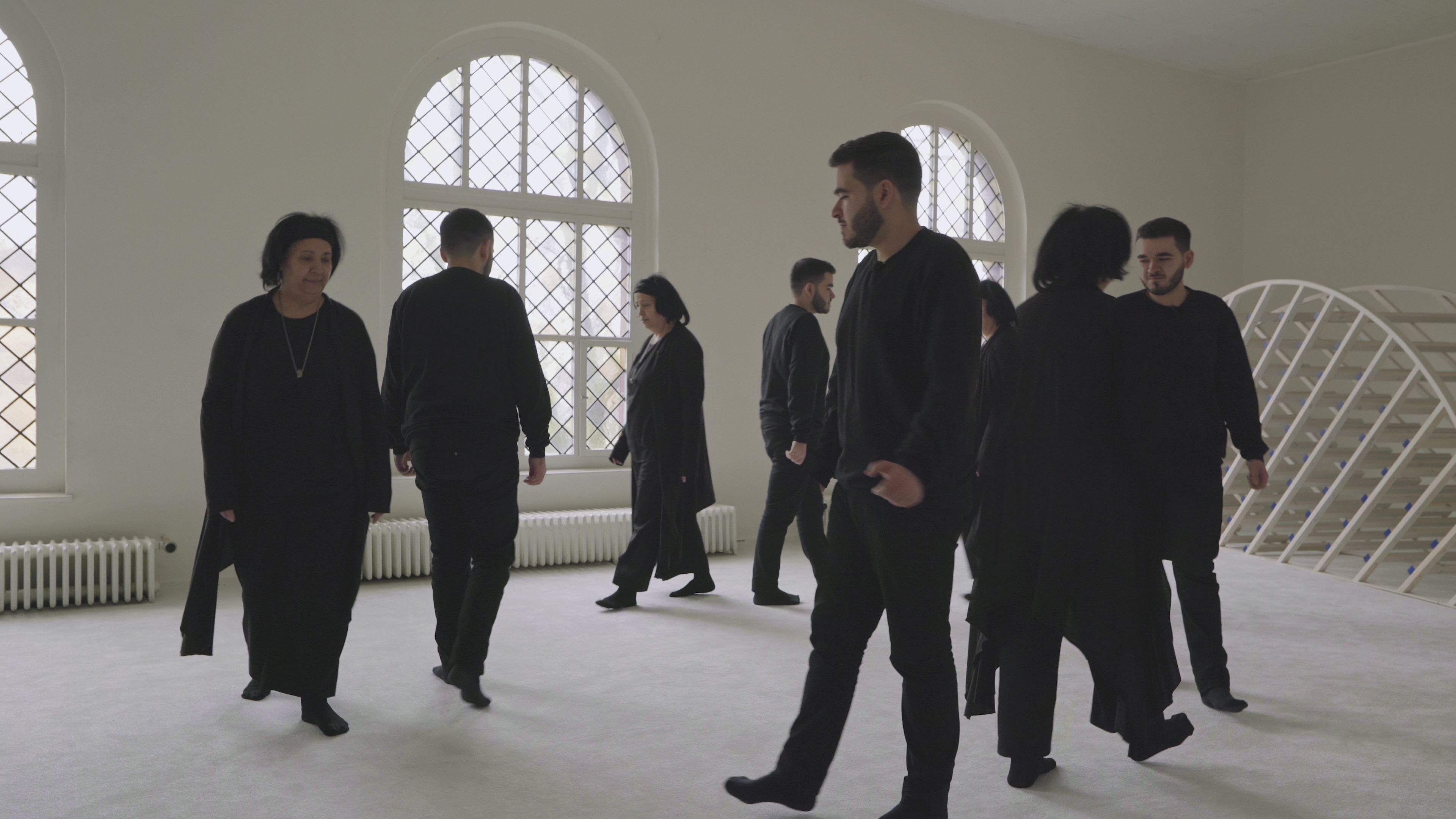  A group dressed in black walking around in a white room