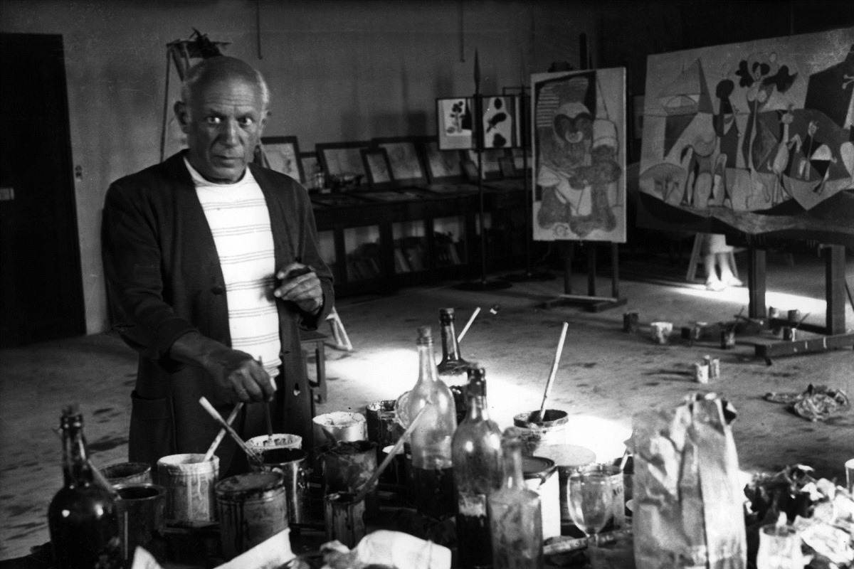 Pablo Picasso in his studio in black and white, with a intense eye looking 