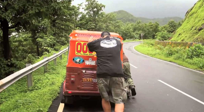 the man is riding on the back of his van