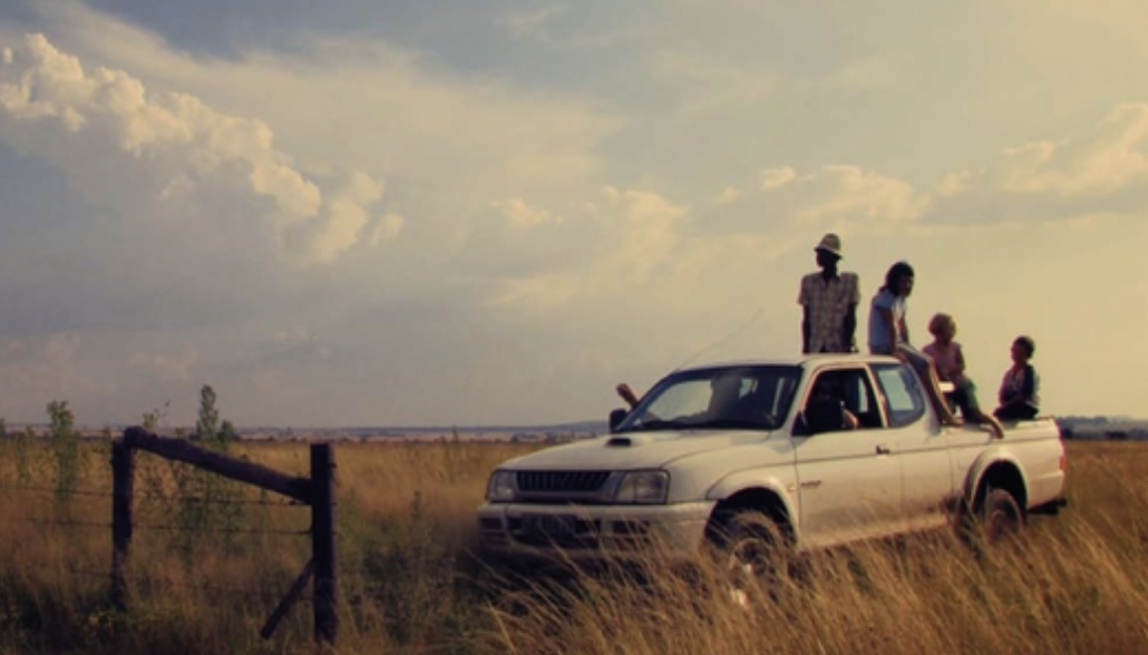 two men and three women on the roof of a pickup truck