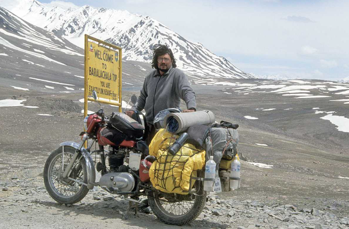 the man on a motorcycle has a large backpack attached to his back