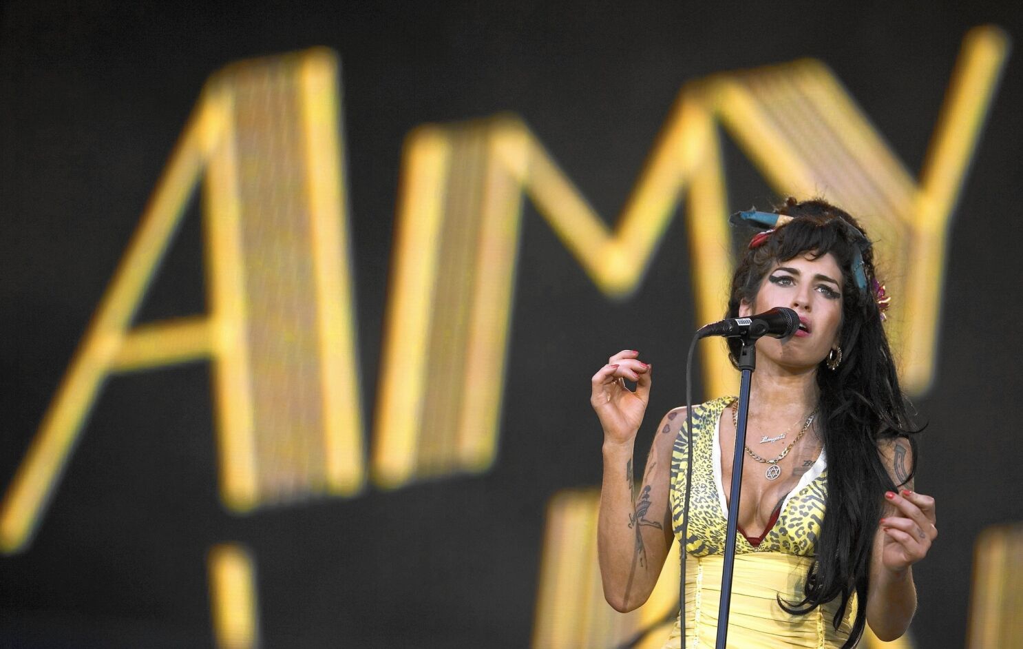 a young black-haired woman sings into a microphone