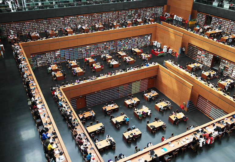 a huge multi-story library with tables and readers