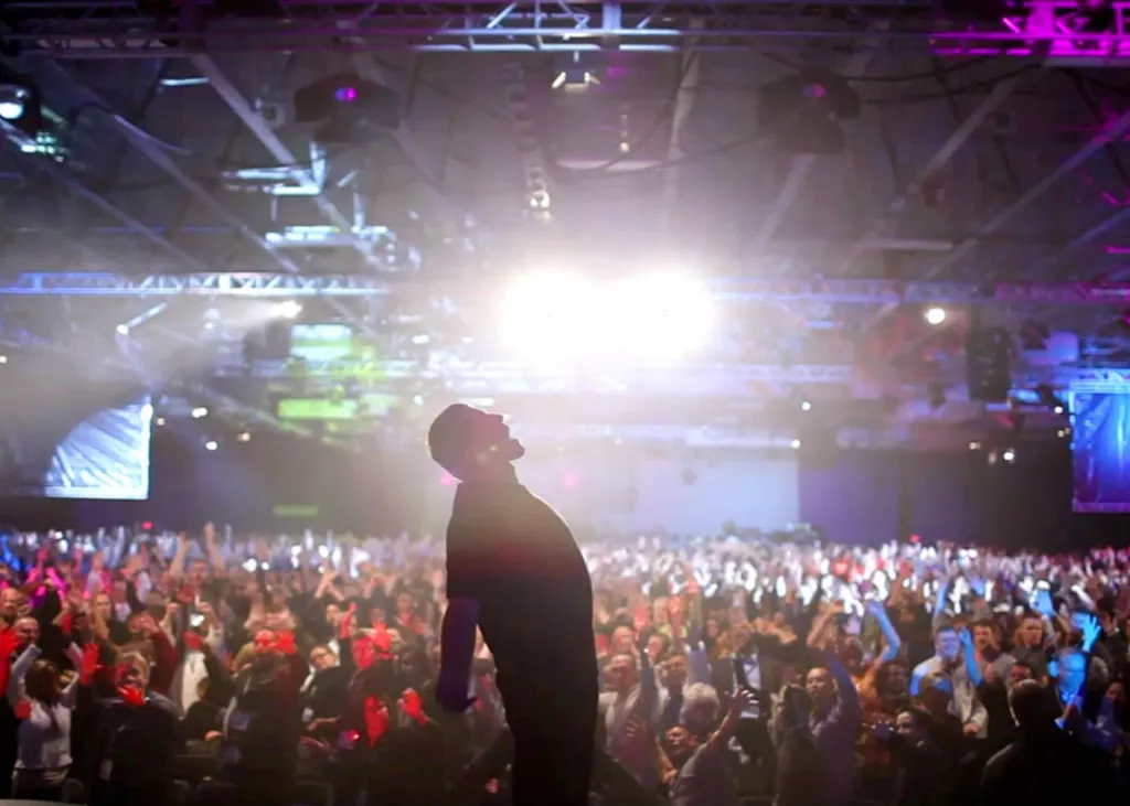 a euphoric man shouts at a concert in front of thousands of people