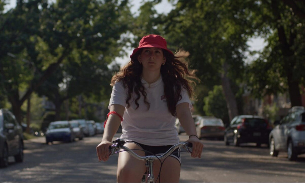 A red hat girl riding a bicycle in a suburb