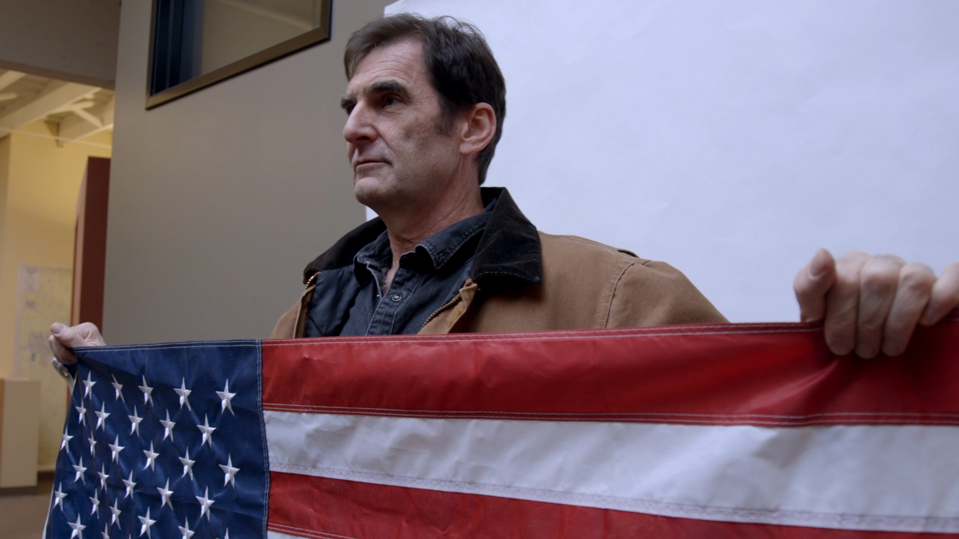 A dark-haired man shows the US flag