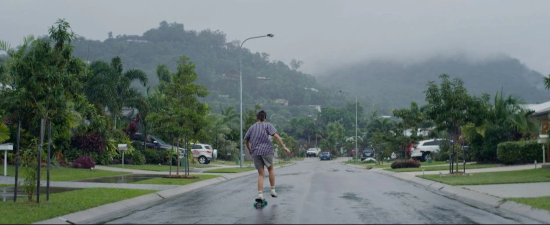a girl with her back turned riding a skateboard in a suburb
