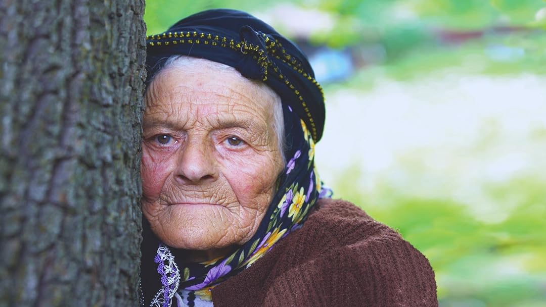 a very old woman peeks out from behind a tree