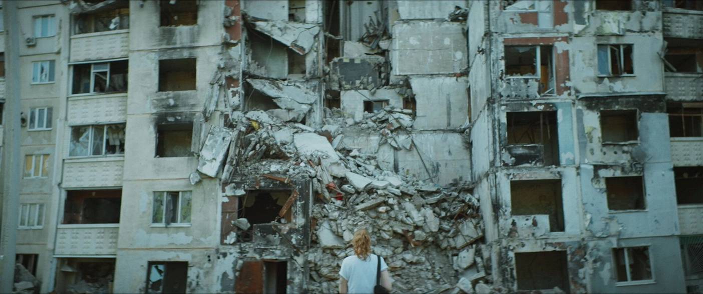 in front of a ruined building a woman with her back turned