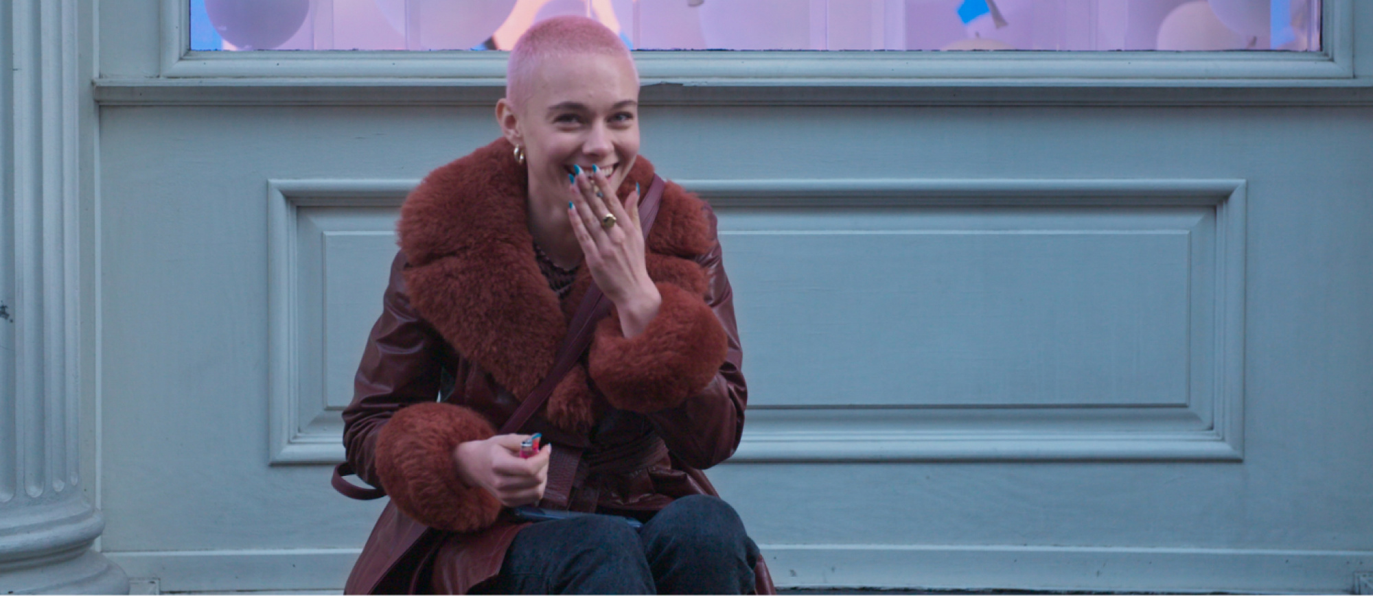 girl with short pink hair smiles while sitting