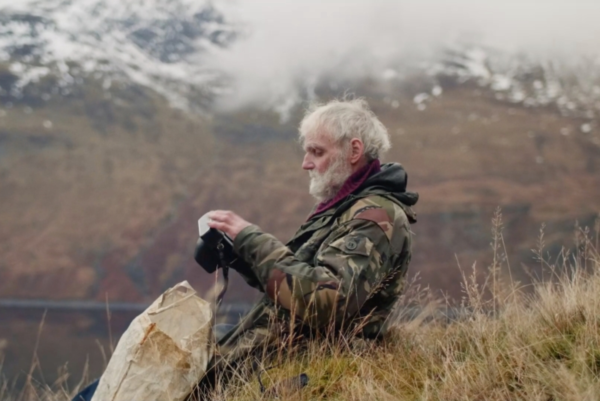 a man with white hair and beard in profile on a mountain