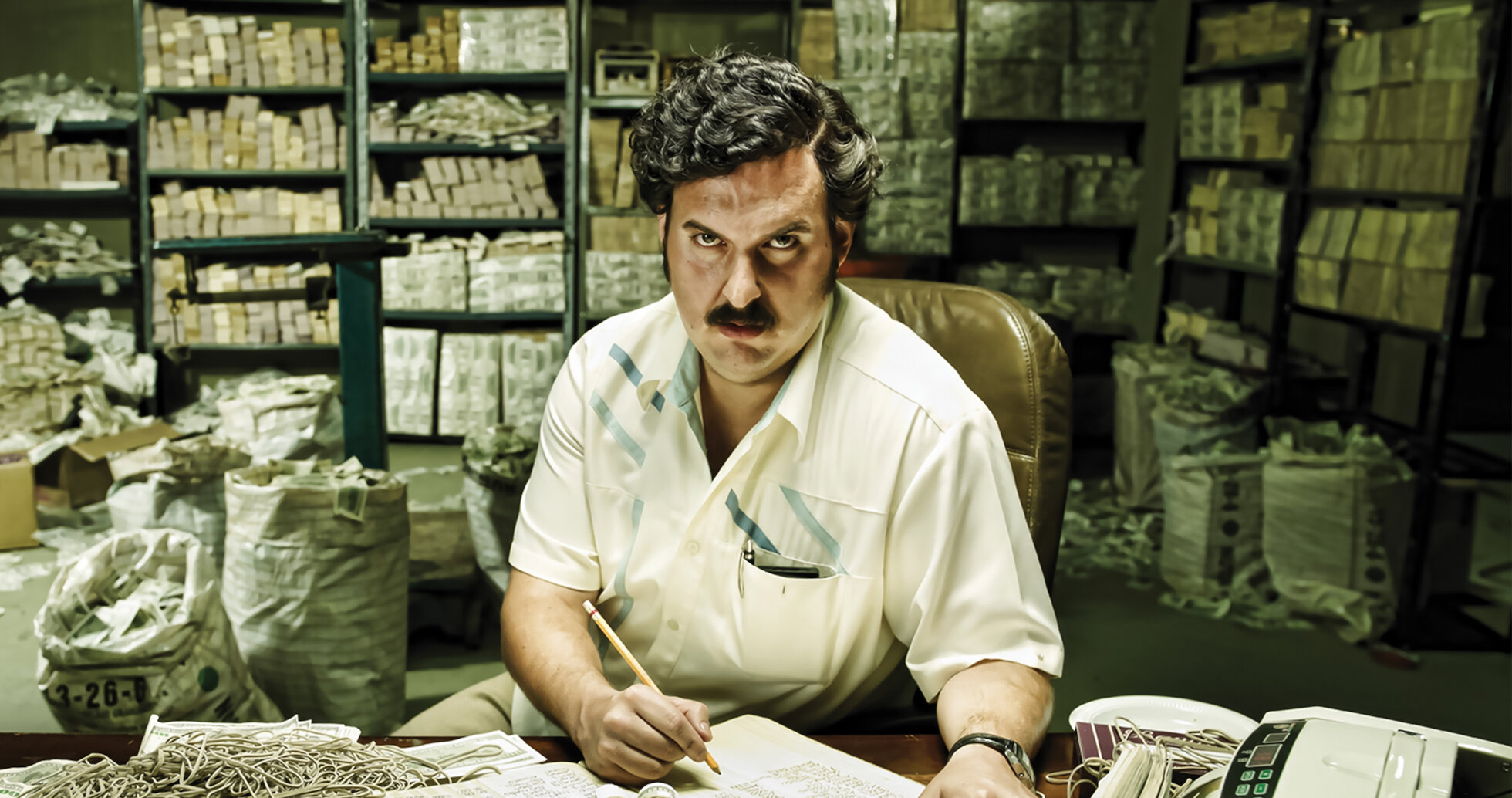 Surrounded by money and inside a vault a man with a mustache