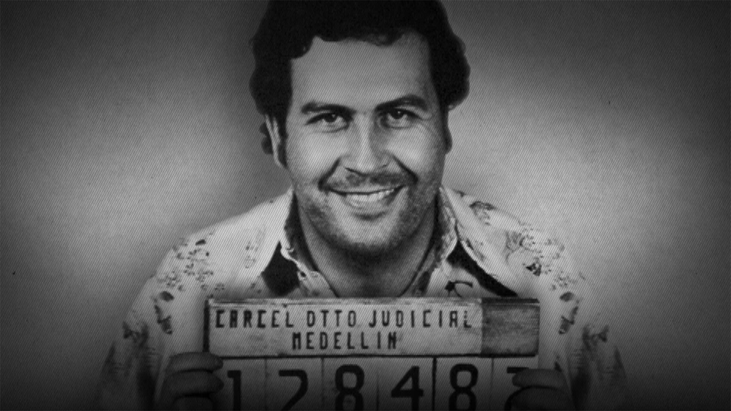 Man in a guayabera smiling and holding a convict's placard