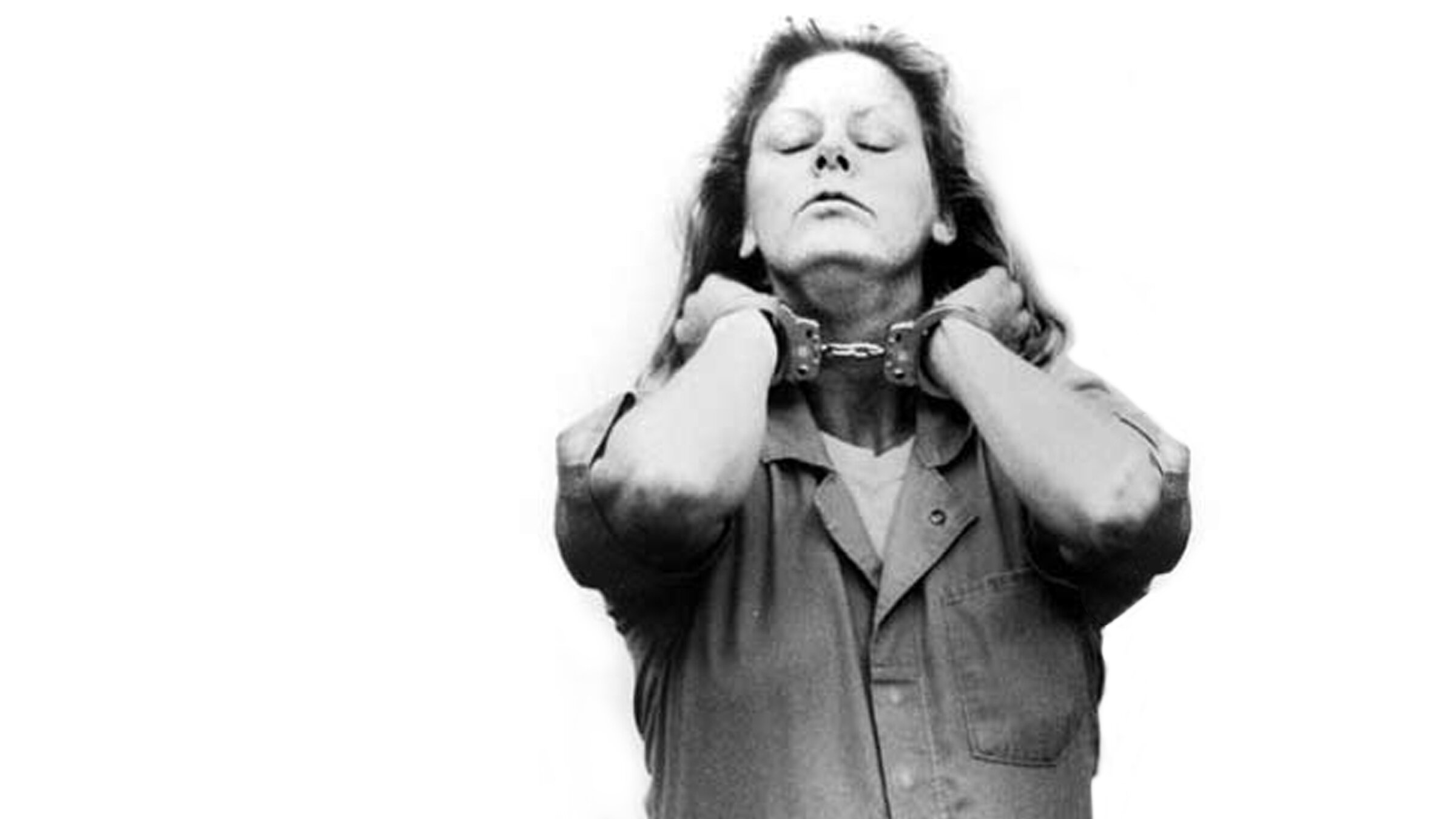 A woman with long hair raises her hands to her neck